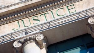 Fachada de tribunal com a palavra Justice esculpida, representando o conceito de diligência judicial vs extrajudicial