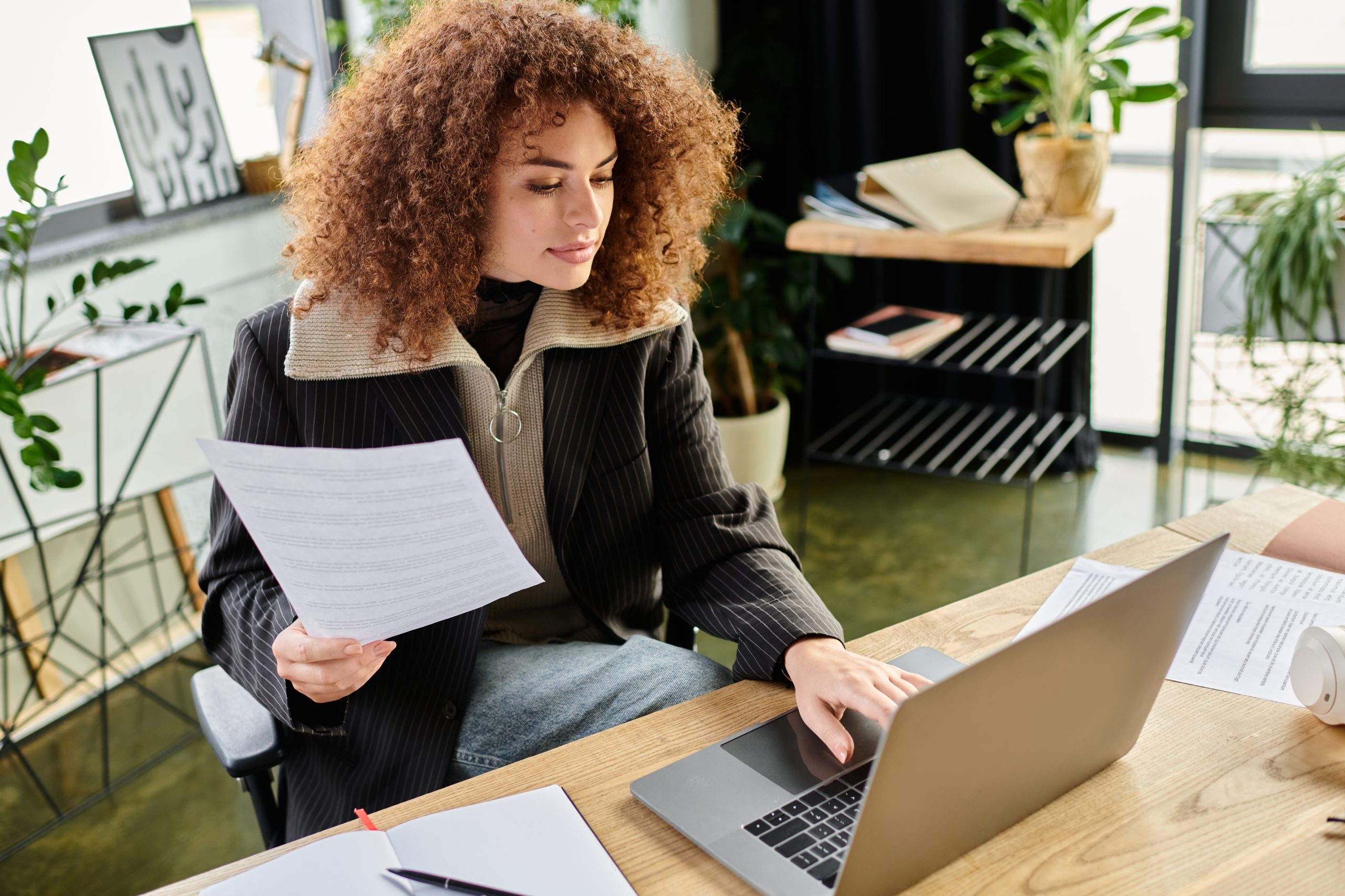 Profissional analisando documento financeiro ao lado do notebook